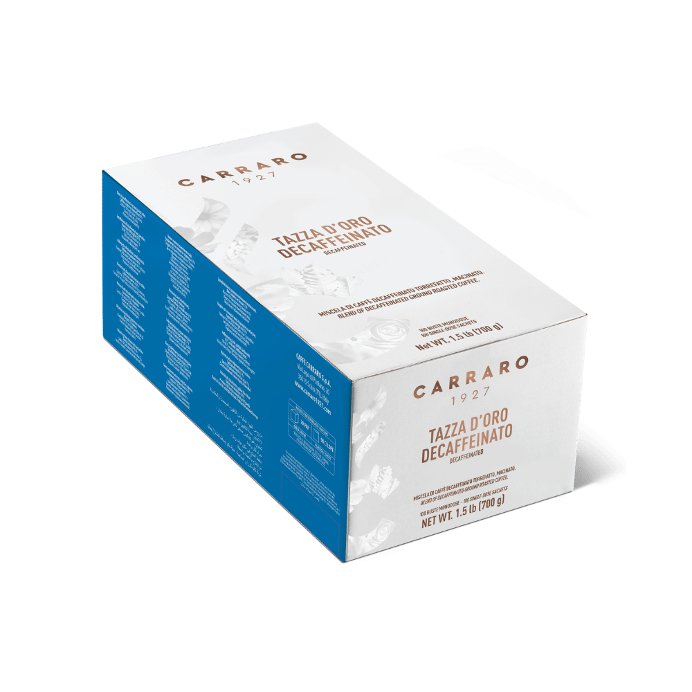 A box of Carraro 1927 Tazza d'Oro Decaffeinato espresso, shown at an angle on a clean white background. The packaging features a white top and front face with elegant brown typography, a solid blue side panel with fine print, and a small white floral illustration.